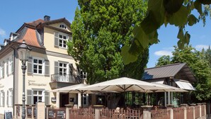 Ein Restaurant mit Außenbereich, einem Balkon und traditioneller europäischer Architektur.