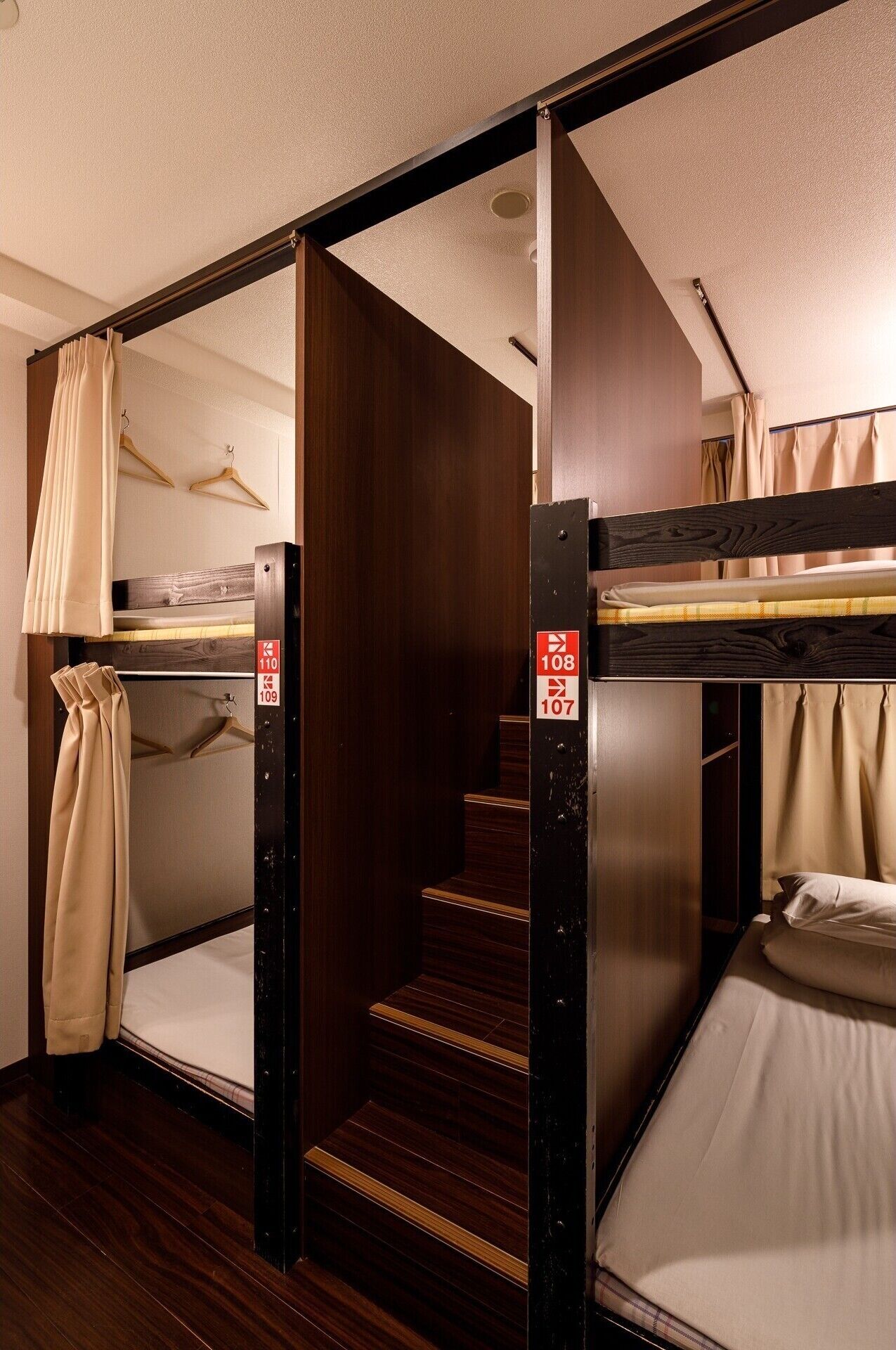 Une chambre avec un lit superposé, un plancher en bois, un escalier et un lit avec un oreiller.