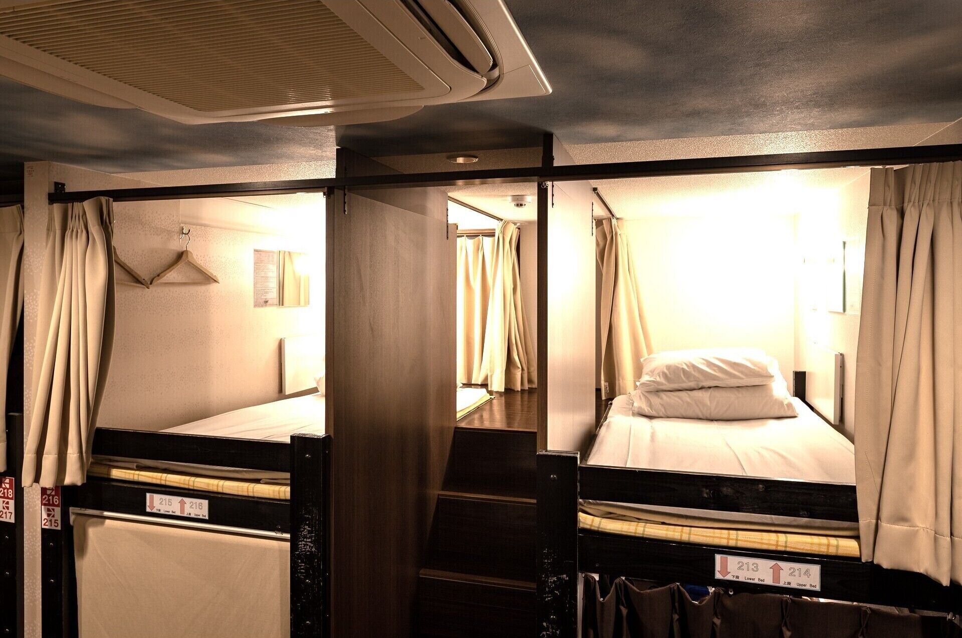 Une chambre avec des lits superposés, un ventilateur de plafond et une fenêtre avec des rideaux.