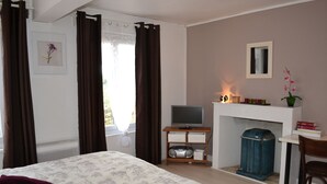 Une chambre à coucher avec un lit, une télévision, une cheminée et un fauteuil.