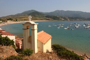Une vue côtière avec un clocher d’église, une plage et des bateaux.