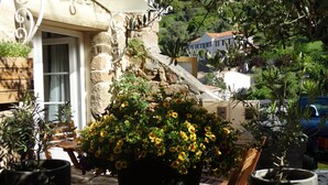 A stone building with a balcony, potted plants, and a view of a green landscape. - APPIETTO, character house near Ajaccio in Corsica. "Between sea and maquis" (Appietto)