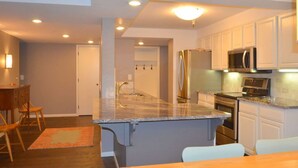 A modern kitchen with granite countertops, stainless steel appliances, and white cabinetry. - True Ski-in Ski-Out Luxury 3bd with Huge views from 5th floor end unit (Steamboat Springs)