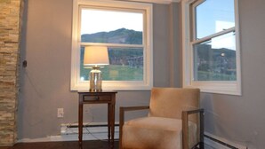 A room with a view of a mountain and a lake, a lamp on a small table, and a chair. - True Ski-in Ski-Out Luxury 3bd with Huge views from 5th floor end unit (Steamboat Springs)