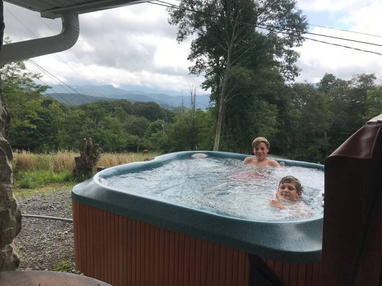 A hot tub outdoors with a scenic view of mountains and trees.