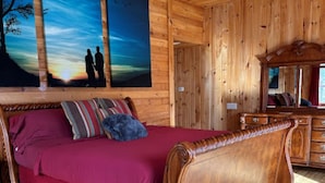 A wooden cabin bedroom with a large bed, a ceiling fan, and two paintings on the wall. - KastleRock Brand new 5 min to Slopes PoolTable Jacuzzi VIEWS PRIVATE sleep15 (Banner Elk)