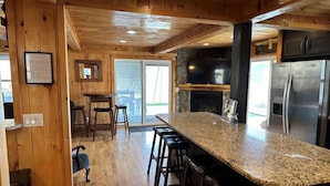 A kitchen with wooden walls, a granite countertop, and a stainless steel refrigerator. - KastleRock Brand new 5 min to Slopes PoolTable Jacuzzi VIEWS PRIVATE sleep15 (Banner Elk)