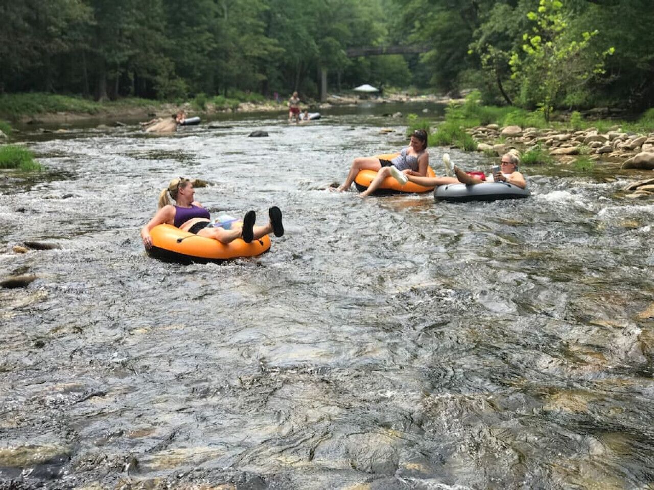 Personas flotando en un bote inflable en un río rodeado de rocas y vegetación.