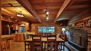 L’intérieur d’un chalet en bois comprend un coin repas, une cuisine et une cheminée.