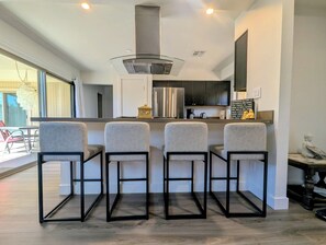 A modern kitchen with a central island, bar stools, and a large window providing natural light. - CENTRALLY LOCATED WITH HOT TUB: Zen Garden - Your Sedona Oasis Awaits (Sedona)