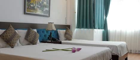 Una habitación de hotel con dos camas, un cuadro en la pared y una ventana con cortinas.