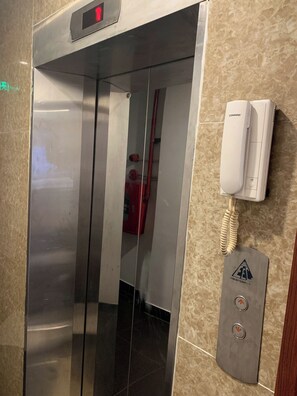 An elevator with a digital display, a wall-mounted phone, and emergency equipment. - Maison D'Hanoi Hotel (Hanoi)