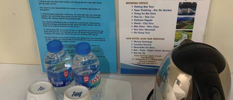 A hotel information board with a list of services and a table with water bottles and teapots.