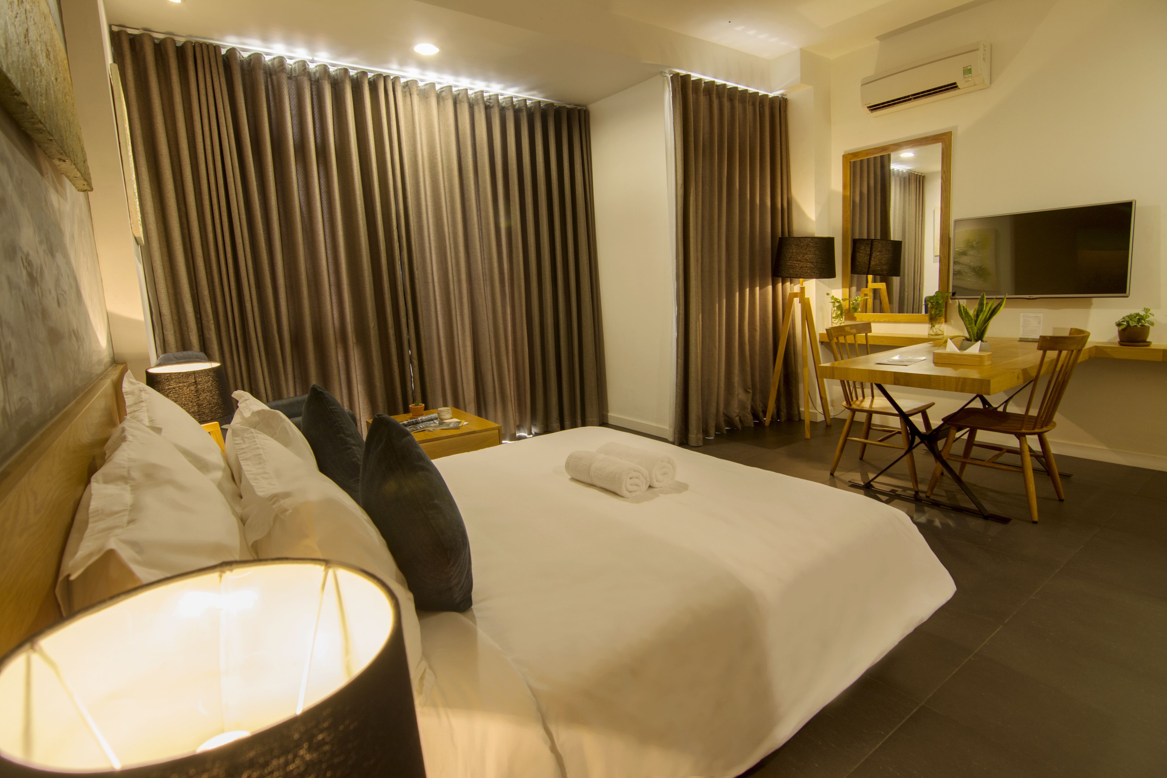 Une chambre d’hôtel avec un lit, un bureau, une chaise, une télévision et des rideaux.