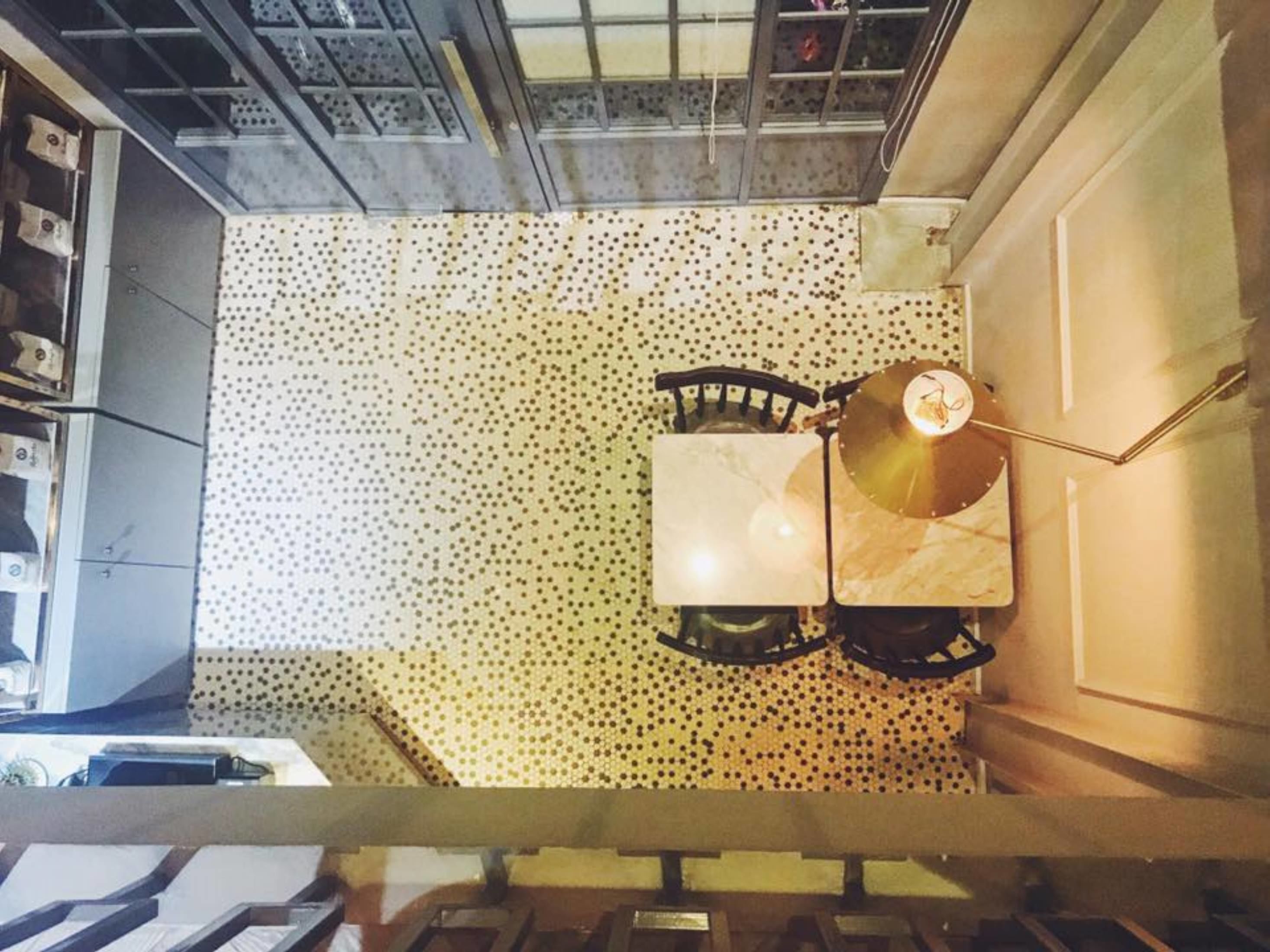 A room with a patterned floor, a table with chairs, and a ceiling with a grid-like structure.