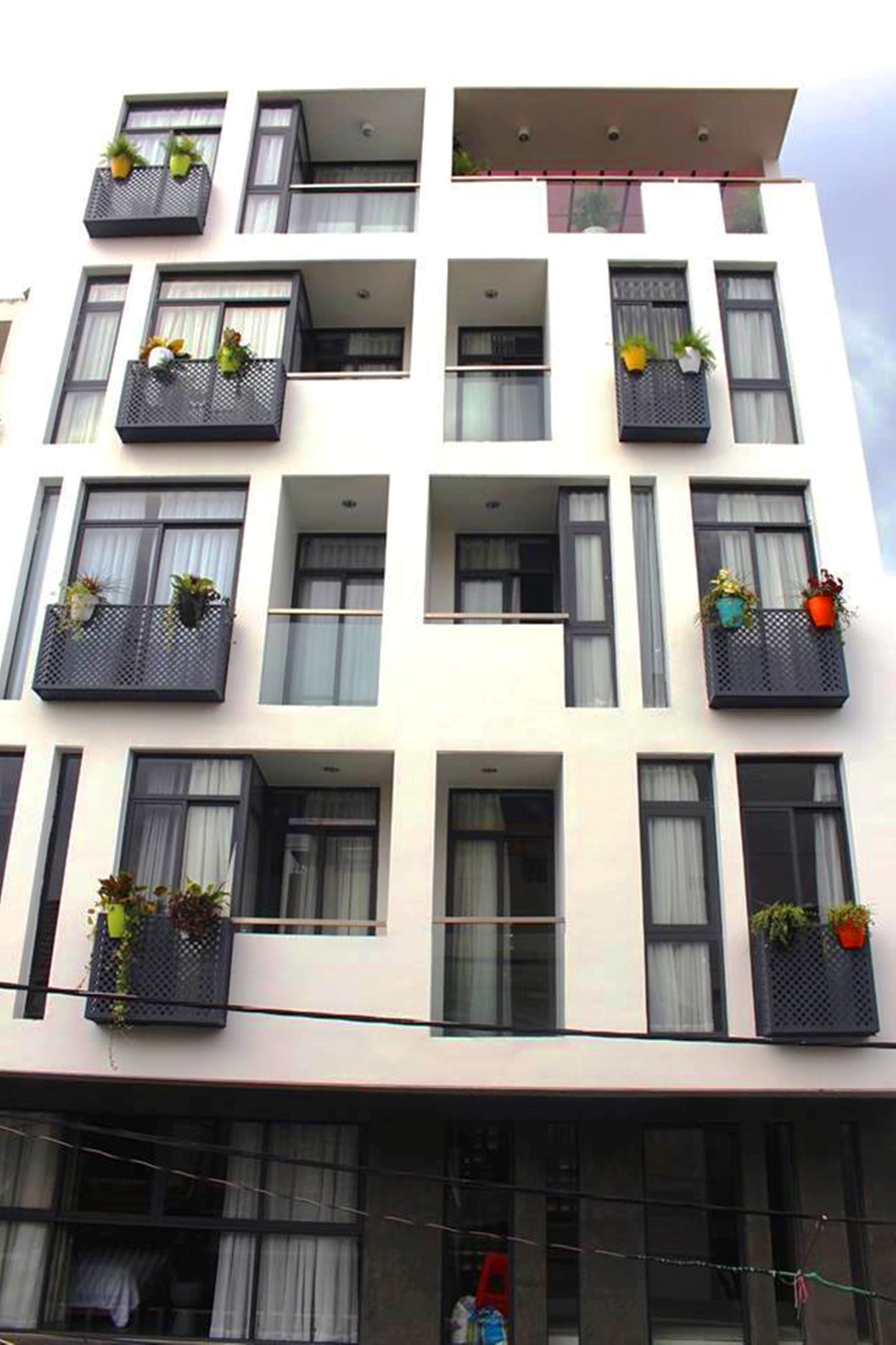 A multi-story building with balconies, each with potted plants.