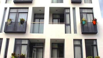 A multi-story building with balconies, each with potted plants.
