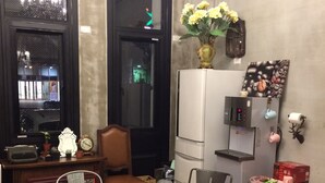 A cozy room with a round table, two chairs, a bookshelf, a coffee machine, and a decorative vase with flowers. - Angelwings (Hualien City)
