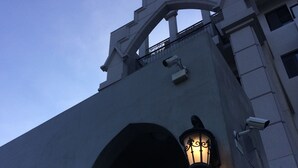 A building with a large arched entrance, two wall-mounted lanterns, and a surveillance camera. - Angelwings (Hualien City)