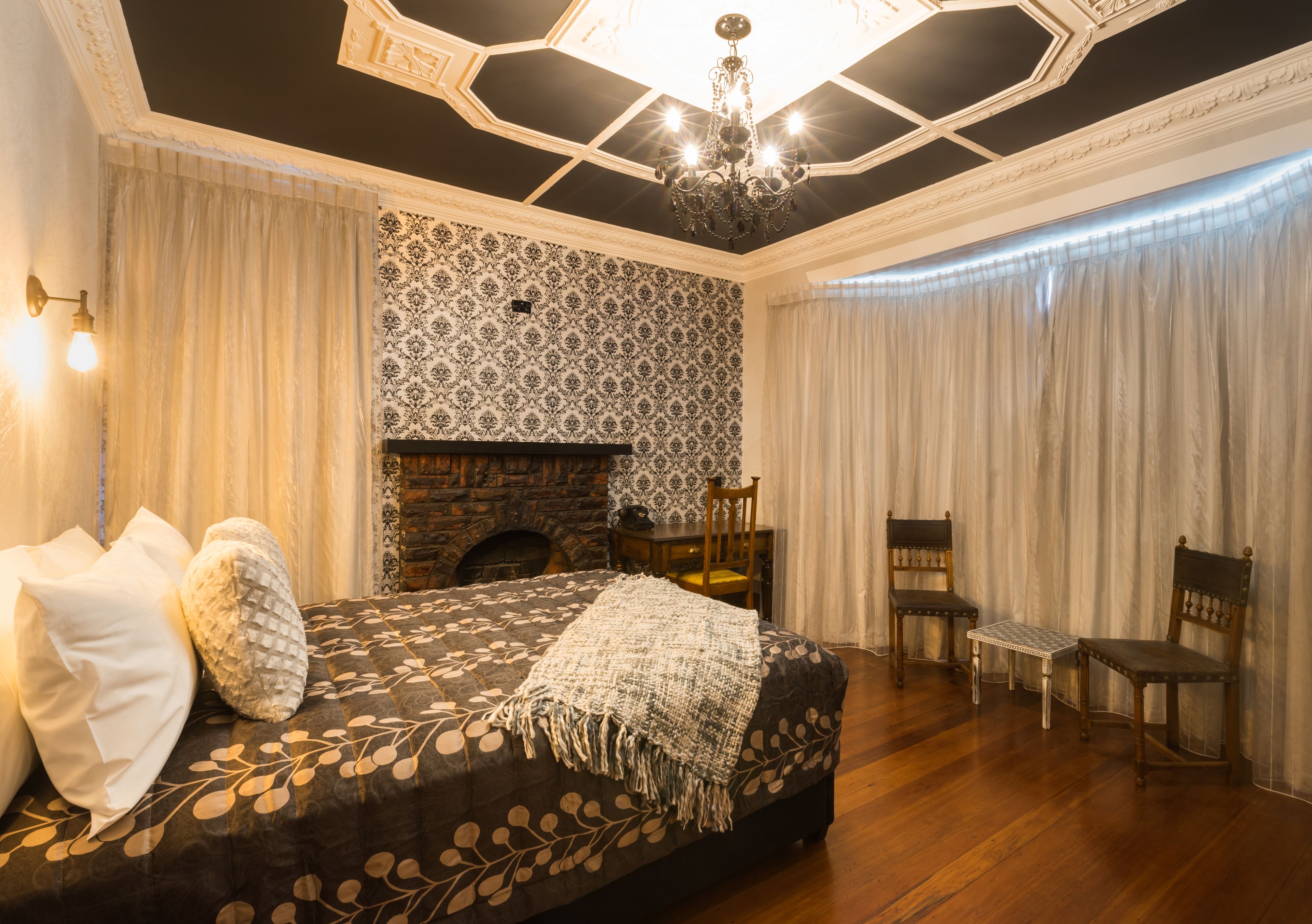A bedroom with a large bed, a fireplace, and a chandelier.