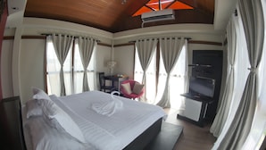 A hotel room with a large bed, a desk with a chair, a TV, and curtains. - Villa Del Rey Resort CamSur powered by Cocotel (Pili)