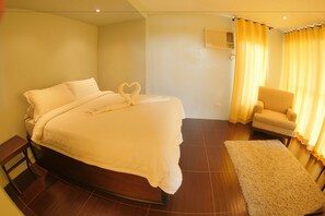A bedroom with a bed, a chair, a rug, and curtains.