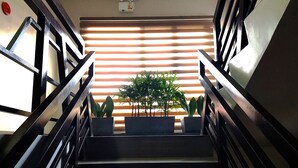 A staircase with black railings and potted plants at the bottom. - Urbantel Hotel (Lucena)