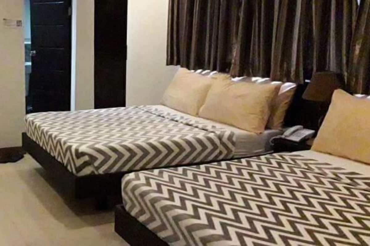 A hotel room with two beds, a desk, and a chair.