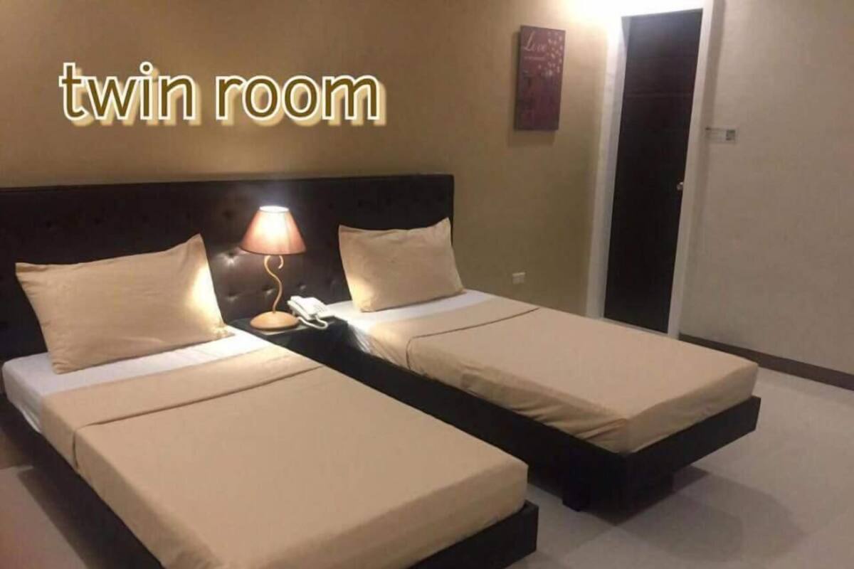 A twin room with two beds, each with a pillow and a bedside lamp.