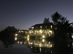 A waterfront property with a large house, a dock, and a reflection in the water.