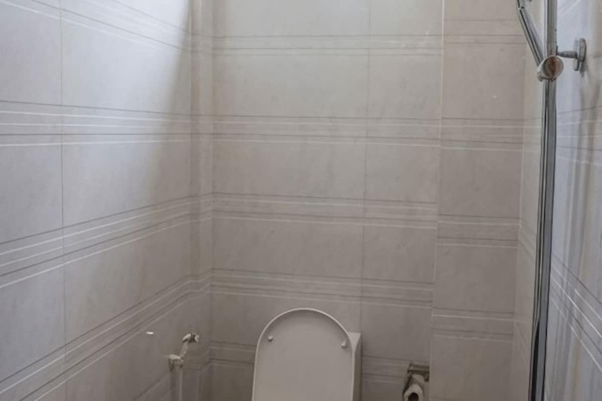 Un baño con paredes de azulejos, inodoro y zona de ducha.
