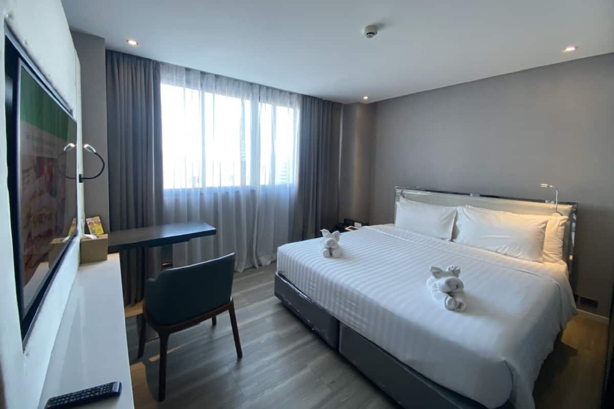 Een hotelkamer met een bed, een bureau, een stoel en een raam met gordijnen.