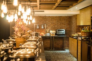 Un buffet avec plusieurs points de service, un mur en briques en arrière-plan et des luminaires suspendus.