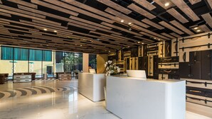 Eine moderne Lobby mit einem polierten Marmorboden, Holzzapfen an der Decke und einer Rezeption mit einer Vase weißer Blumen.