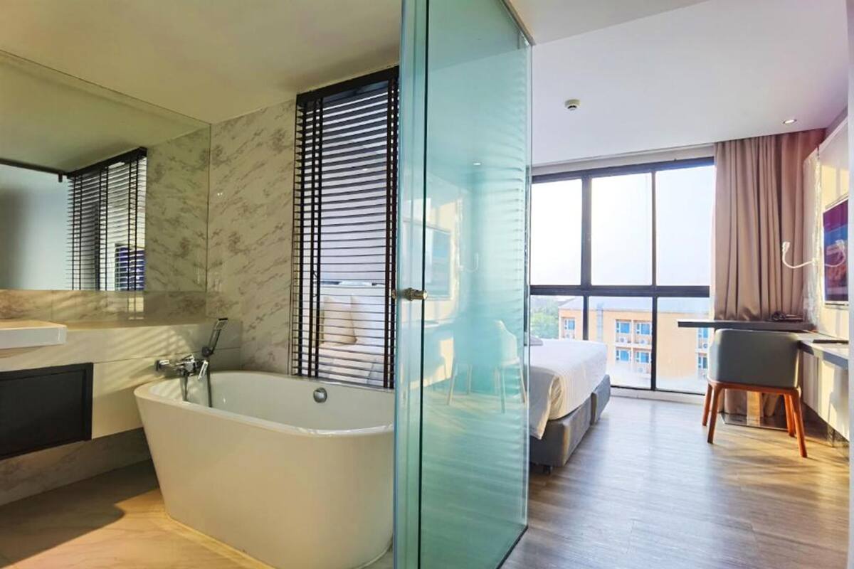 Een moderne badkamer met een vrijstaand bad, een grote spiegel en een douchecabine van glas.