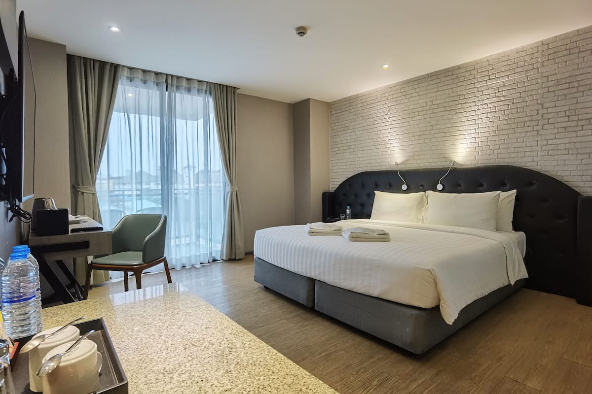 Een hotelkamer met een groot bed, een bureau met stoel, een televisie en uitzicht op de stad.