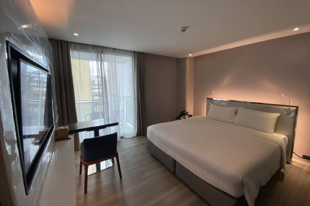 Een moderne hotelkamer met een groot bed, een bureau en een stoel.