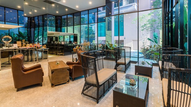 Eine großzügige Lobby mit modernen Möbeln, großen Fenstern und Blick ins Freie.