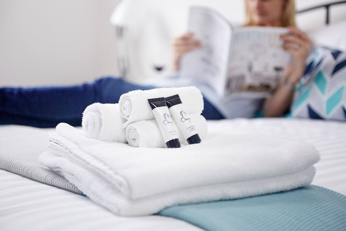 A neatly made bed with folded towels and toiletries.