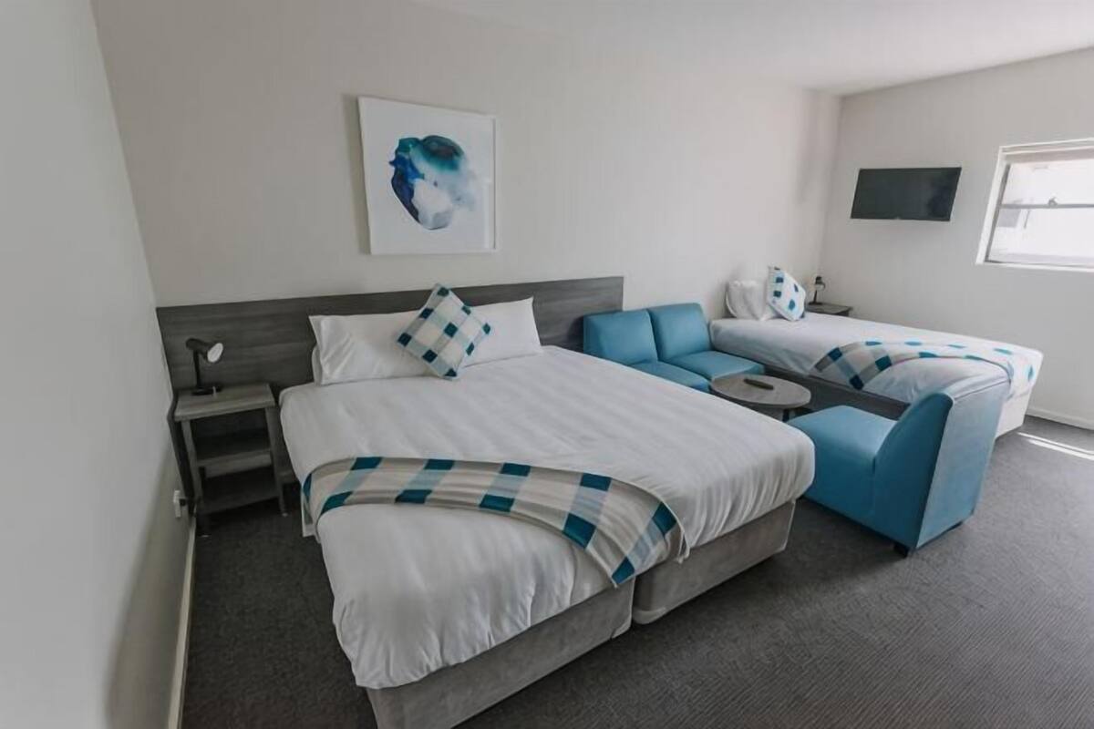 A hotel room with a large bed, a sofa, a desk, and a TV.