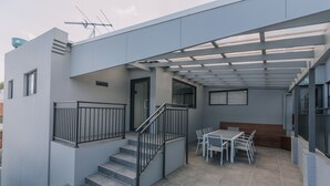 Un edificio moderno con un'area esterna coperta che include una scala, un tavolo da pranzo e sedie.