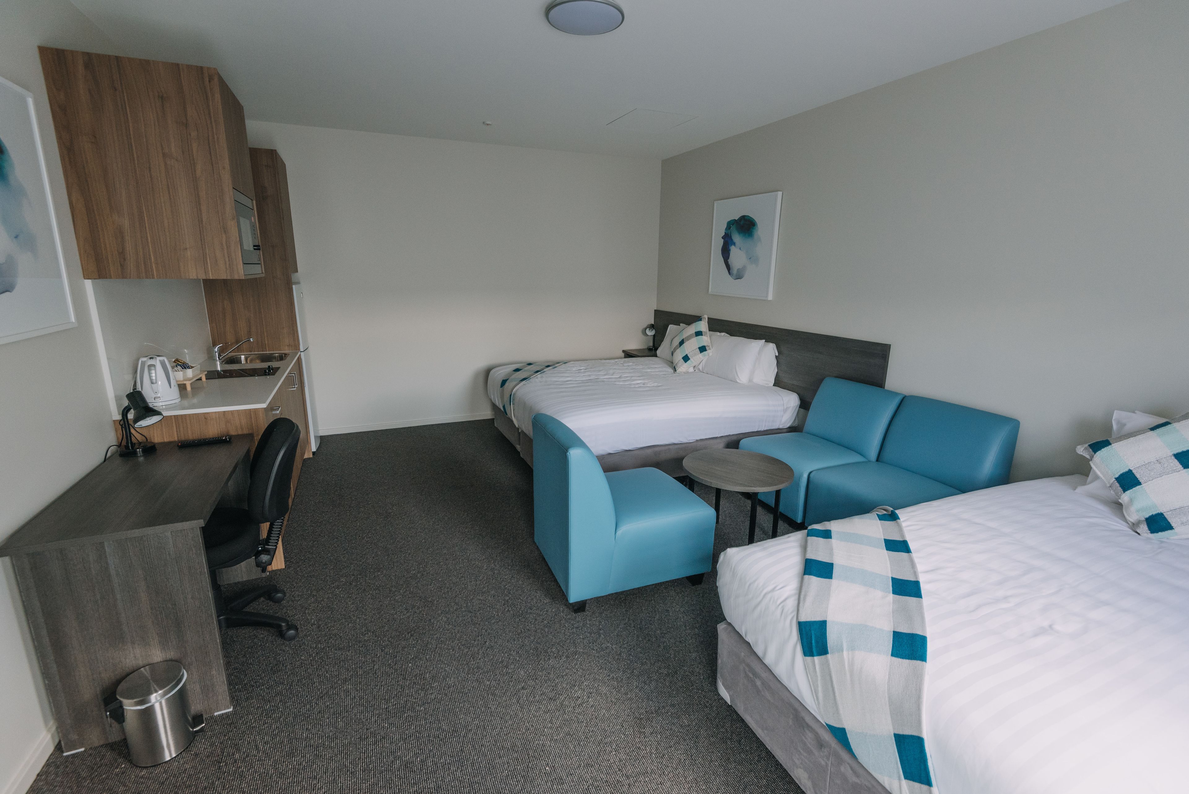 A hotel room with a bed, a sofa, a desk, and a small table.