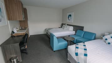 A hotel room with a bed, a sofa, a desk, and a small table.
