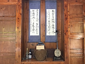 A traditional Japanese room with wooden sliding doors, a shoji screen, a small table with a bottle, a woven bag, and a decorative item. - Makiya Tokusukeya (Nago)