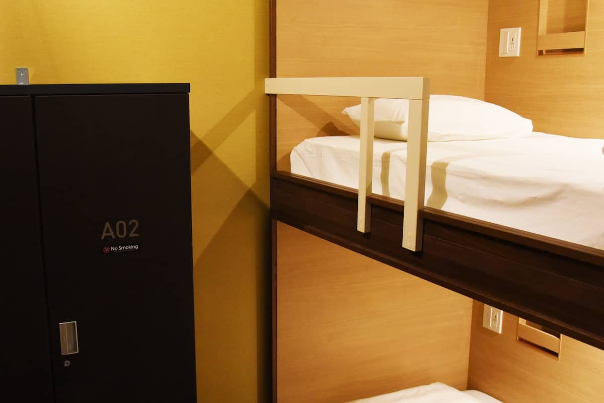 Ein Hotelzimmer mit einem Etagenbett, einem Kleiderschrank und einem kleinen Spiegel an der Wand.