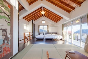 A bedroom with two beds, a large window, and a view of the outdoors.