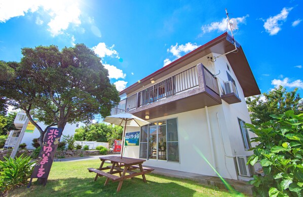 A two-story building with a balcony, a picnic table, and a sign in a foreign language.