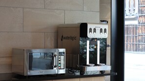 Un distributeur d’eau et un four à micro-ondes sont posés sur un plan de travail.