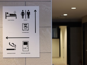 A sign with icons indicating a guest room, toilets, a laundromat, a smoking room, and a vending machine.