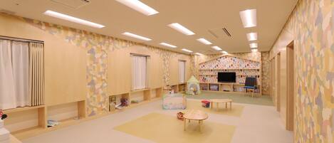 A spacious room with a play area, a television, and a large window with curtains.